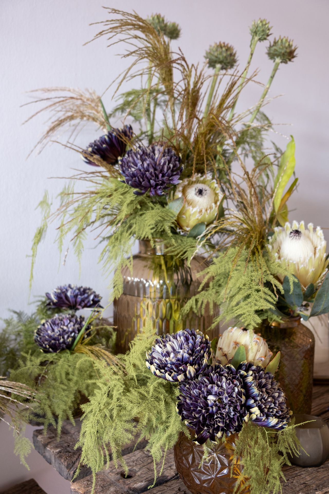 bouquets de fleurs verte et bleu foncé sur table en bois et mur blanc