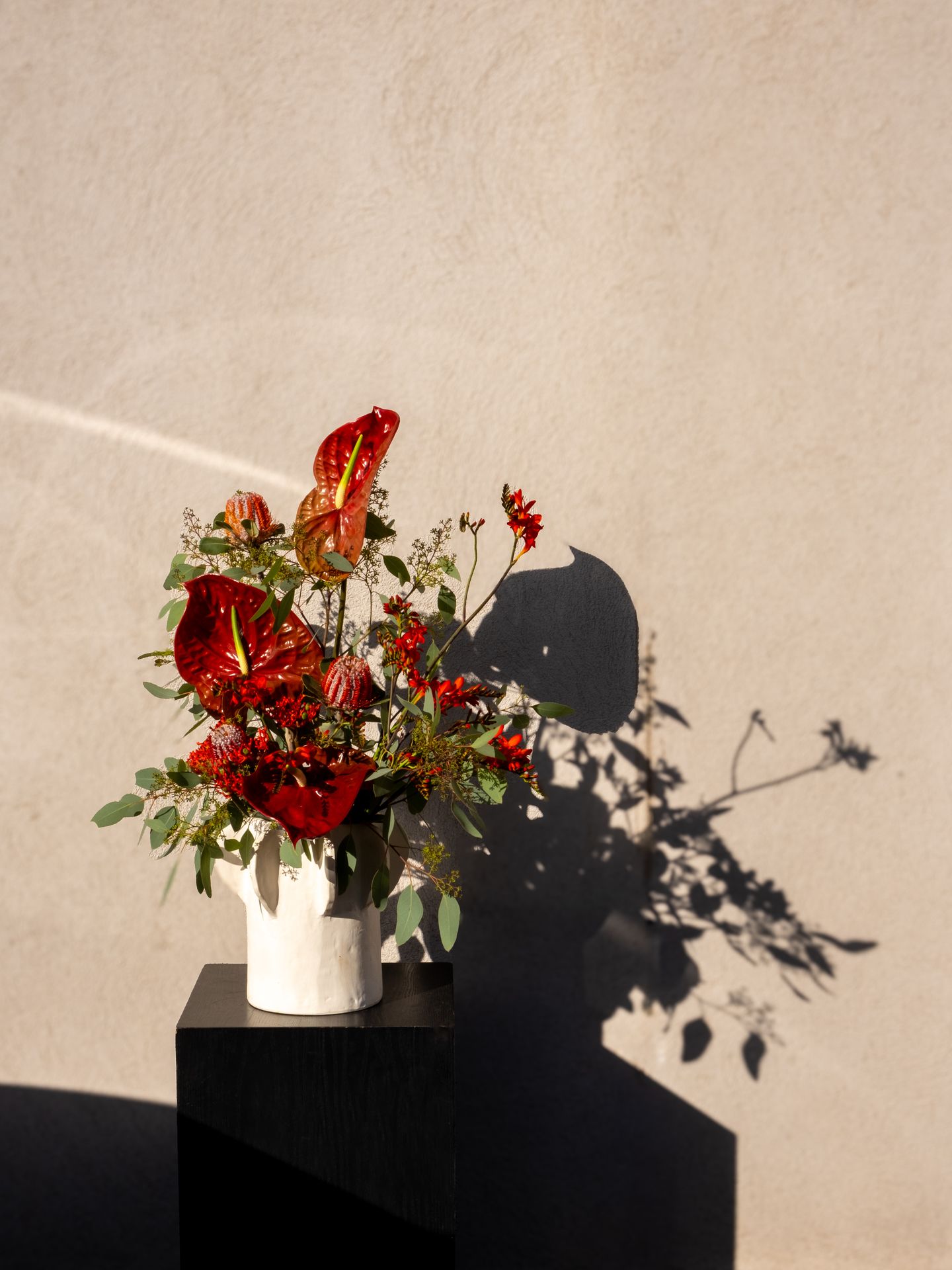 Un bouquet de fleur rouge et vert avec vase blanc