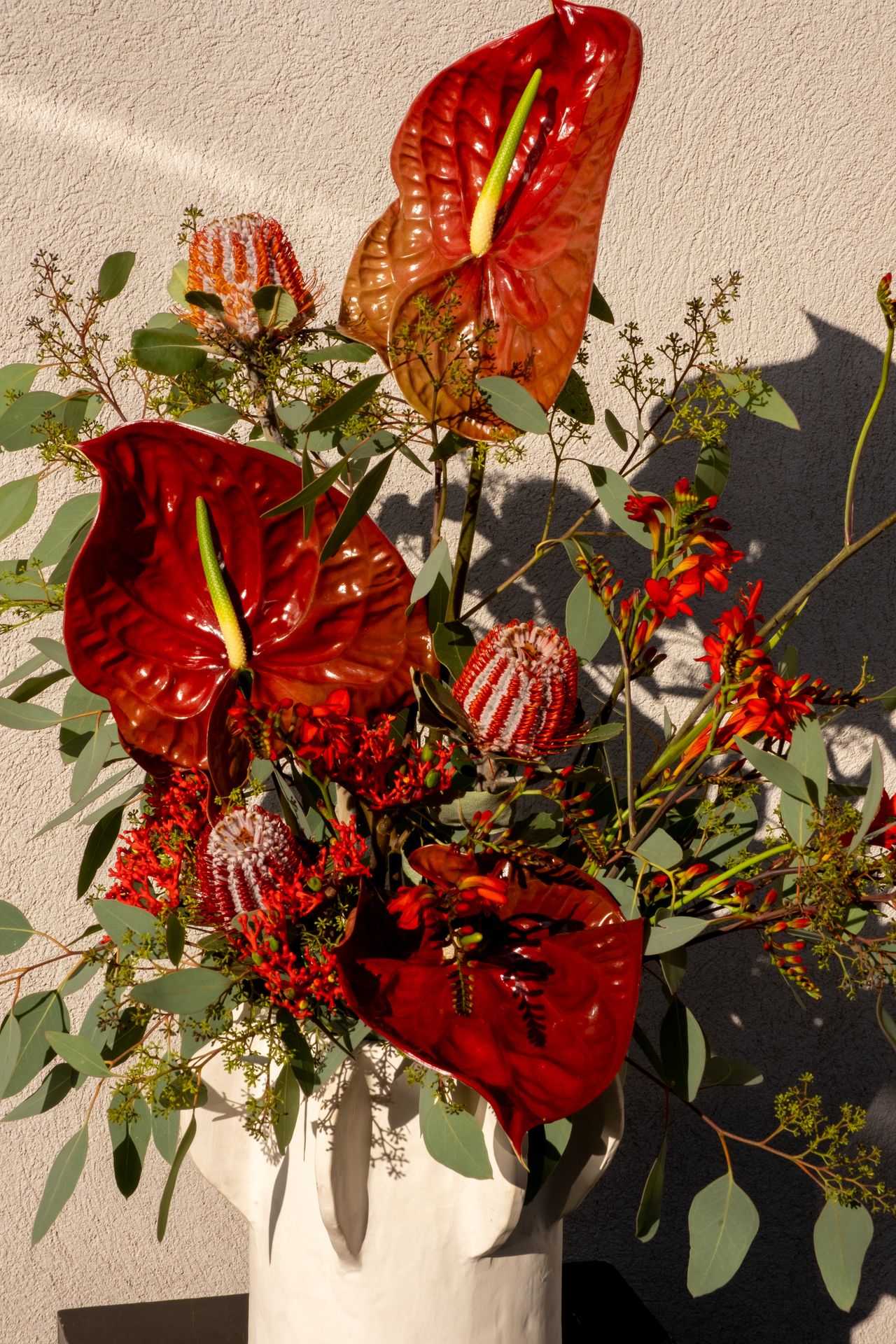 Un bouquet de fleur rouge et vert avec vase blanc