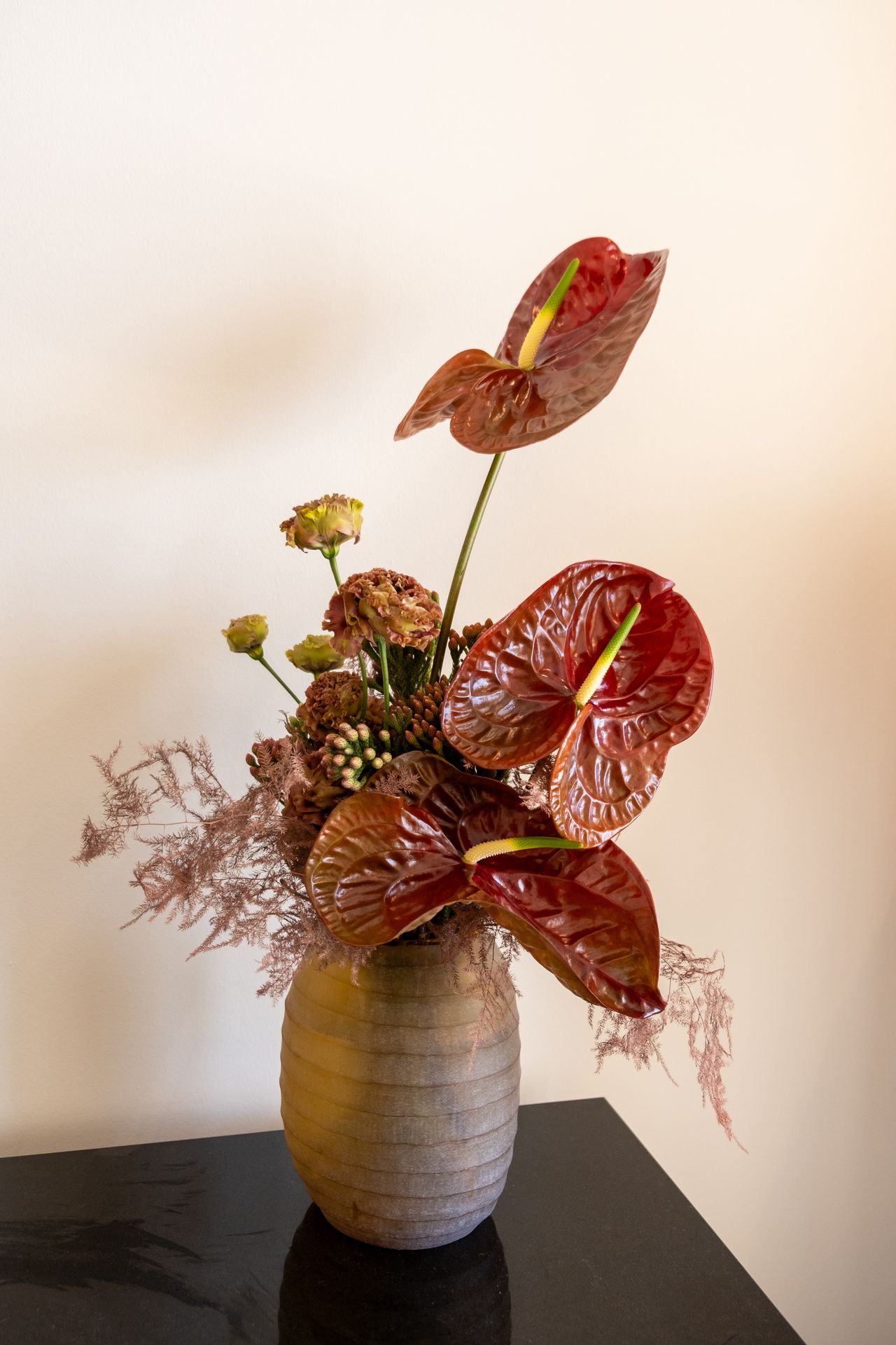 Un bouquet de fleur rouge avec un anthurium et un mur blanc