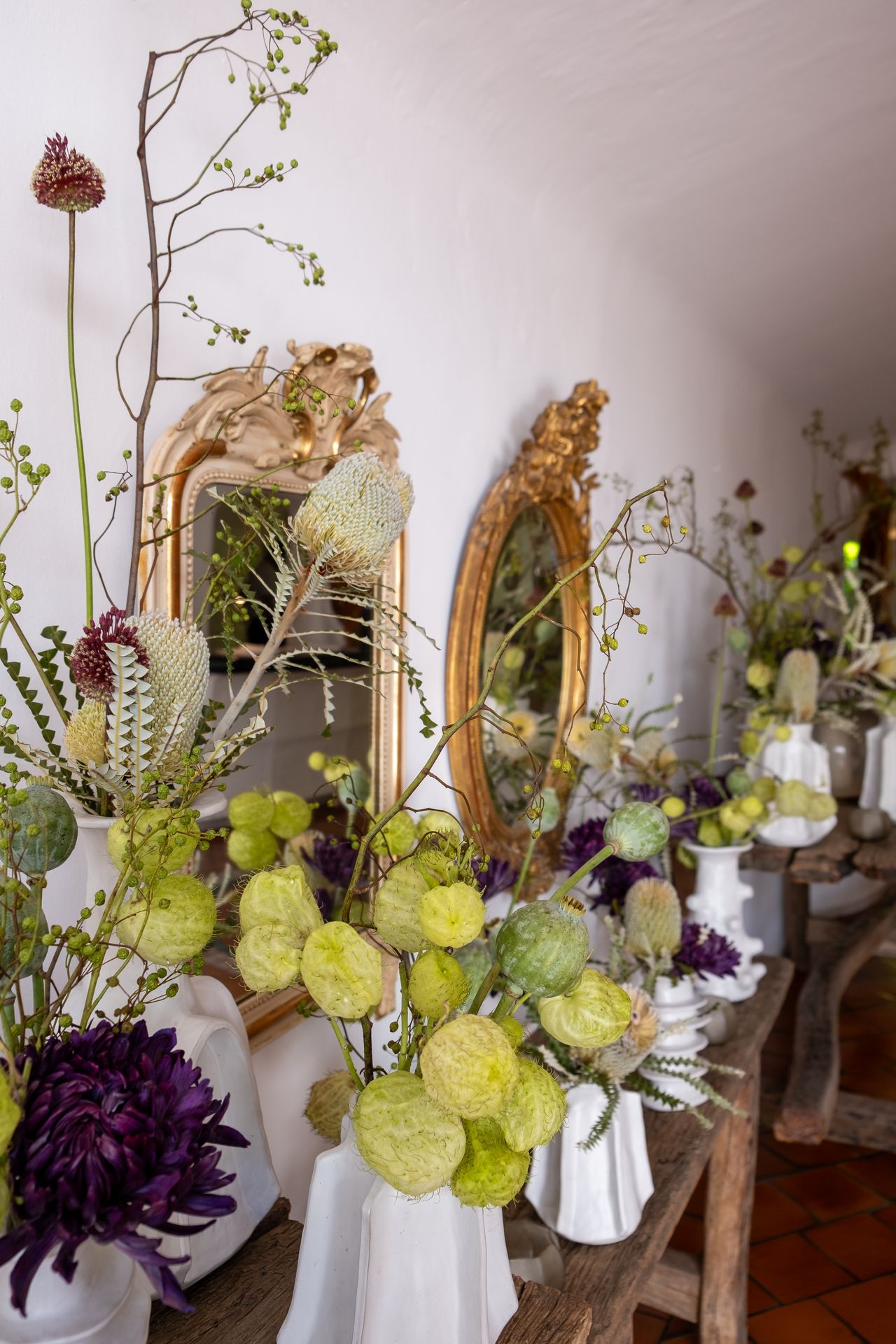 Des bouquets de fleurs verts et violets avec vase blanc et des miroirs