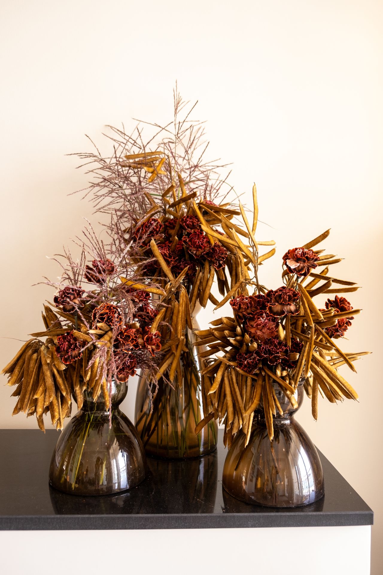trois bouquets de fleur maron avec vase noir