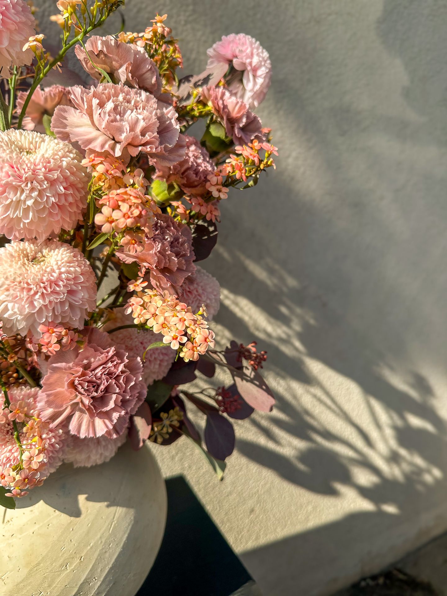 Un bouquet de fleur rose et blanc avec un vase blanc et une table noir