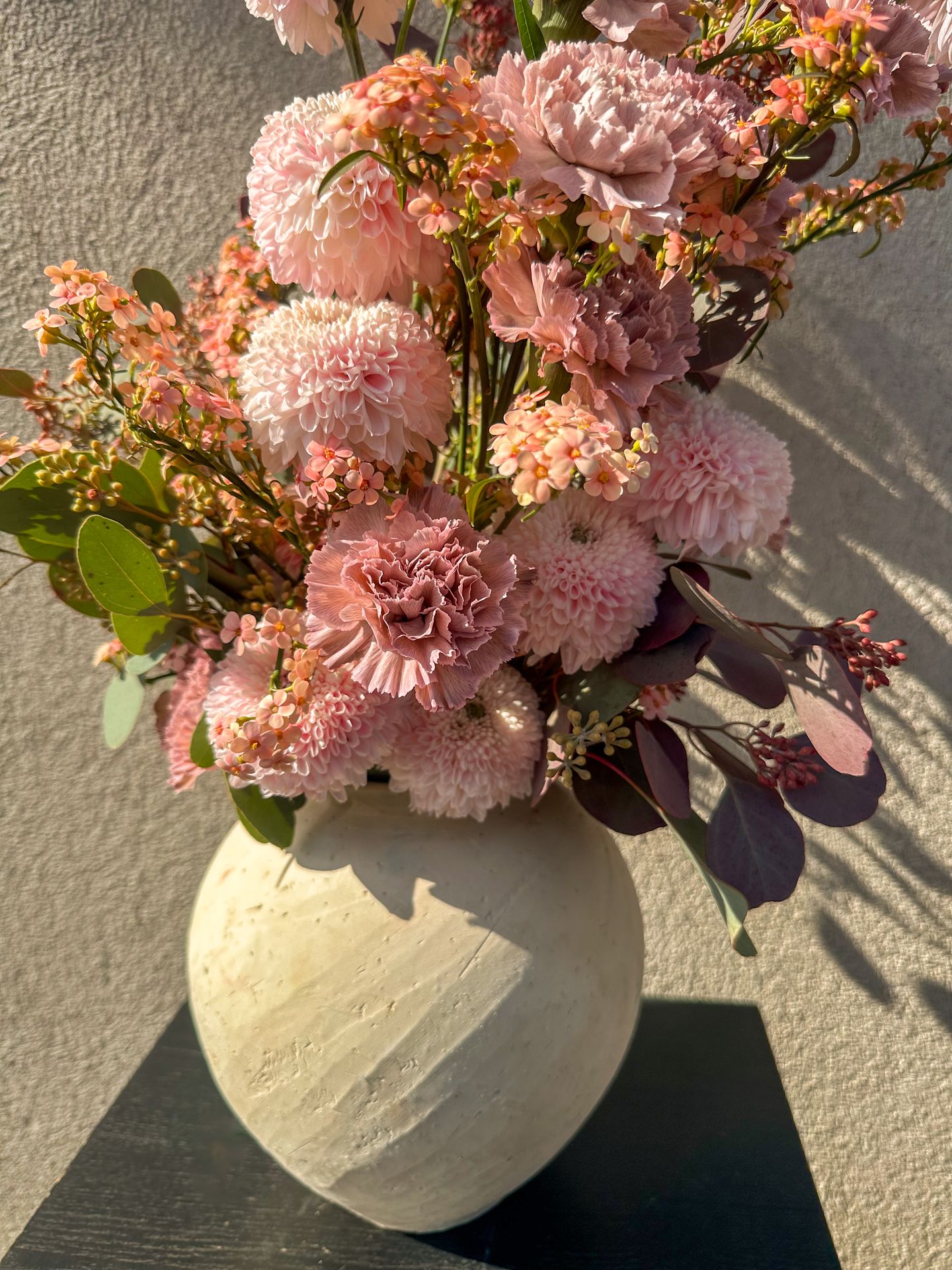 Un bouquet de fleur rose et blanc avec un vase blanc et une table noir