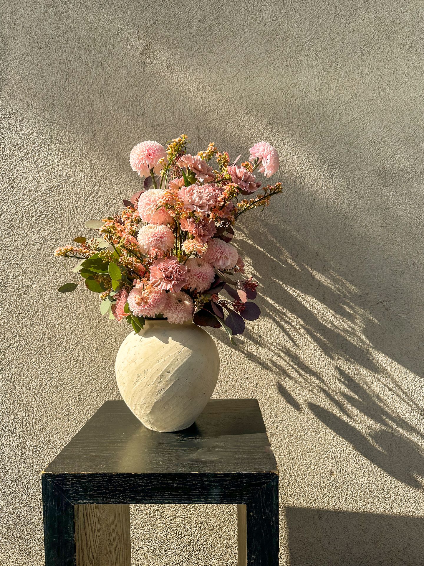 Un bouquet de fleur rose et blanc avec un vase blanc et une table noir