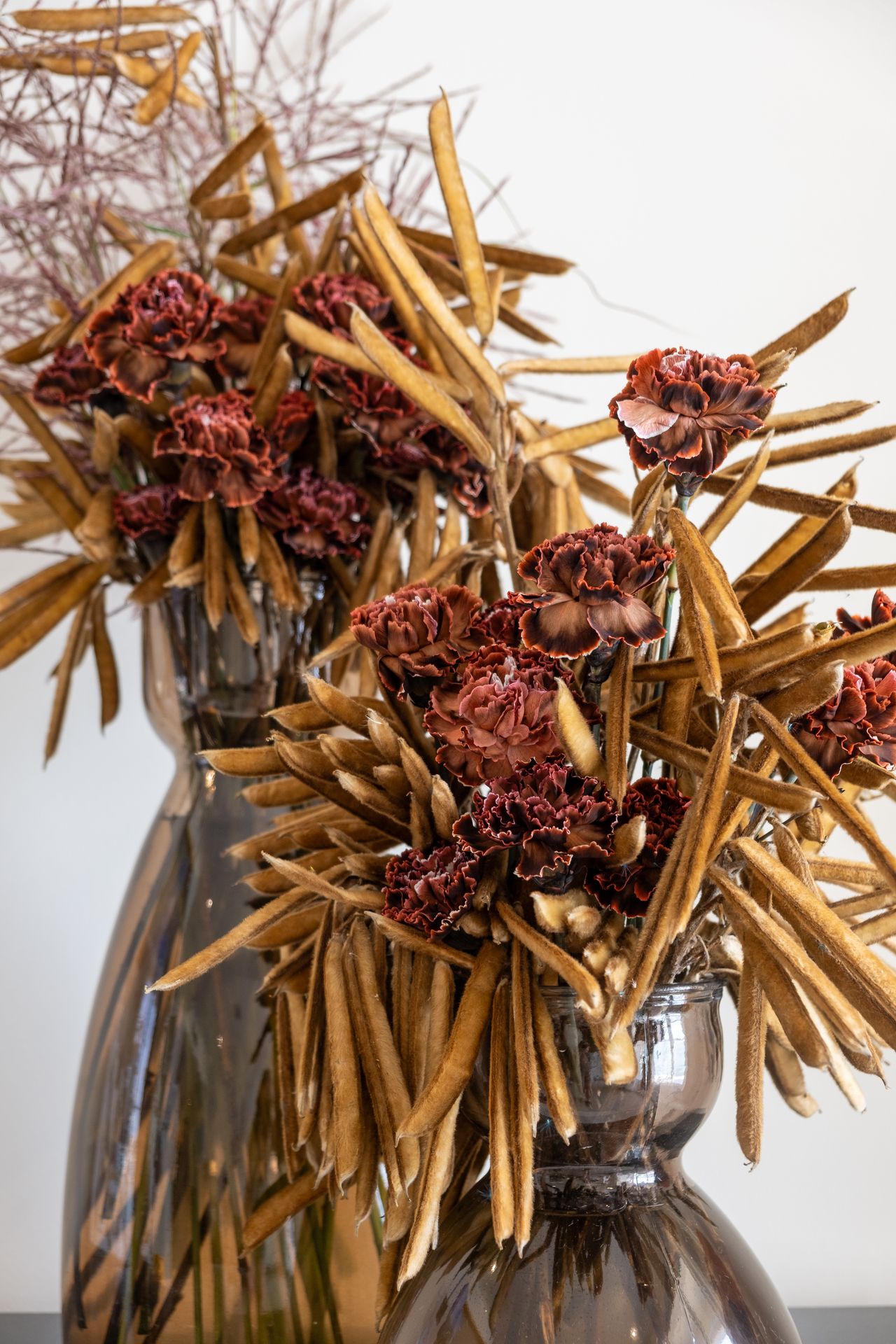 deux bouquets de fleurs maron avec des vases noirs
